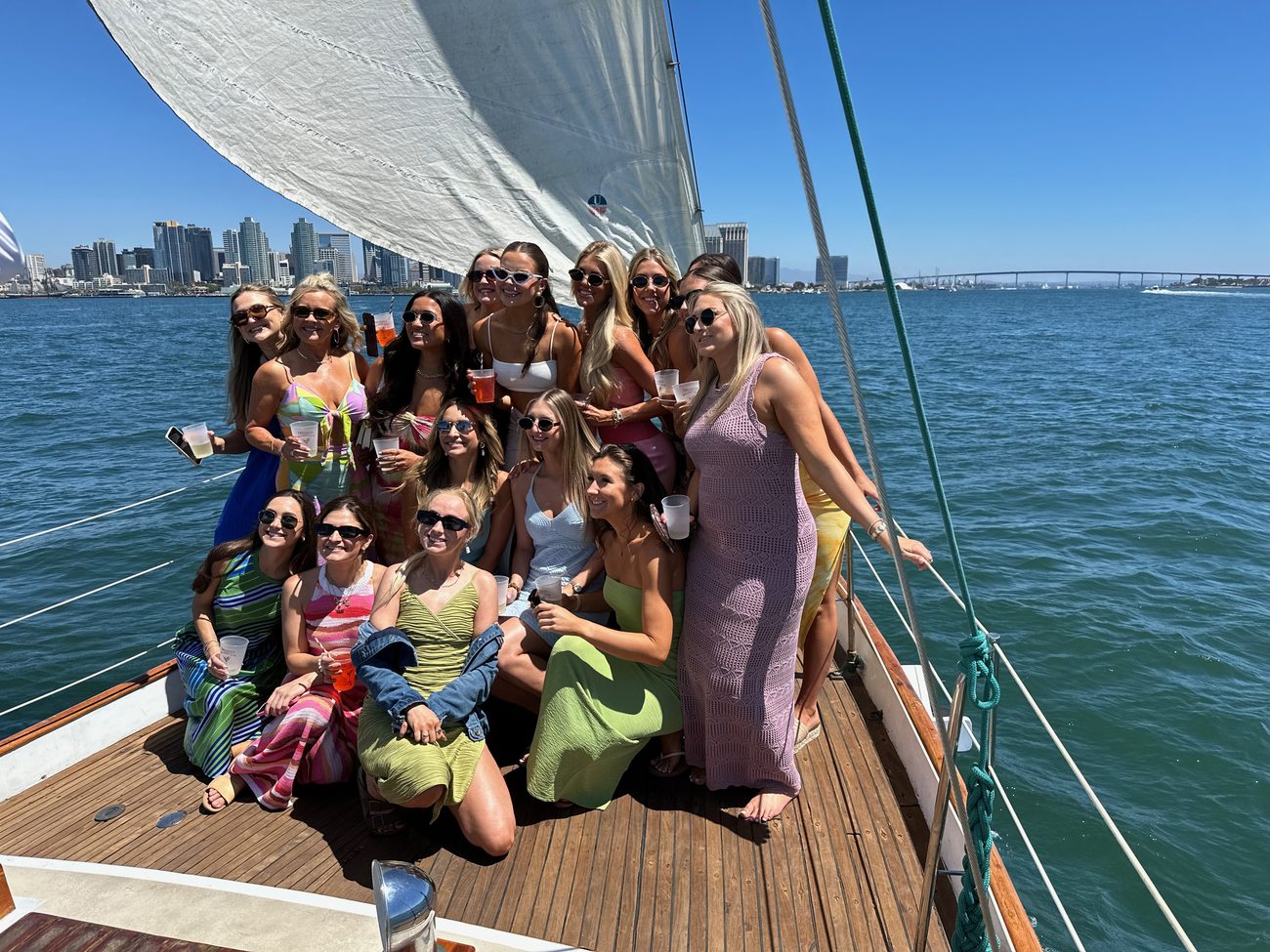 The bride's group posing on JADA's bow with the sails up and the San Diego skyline behind
